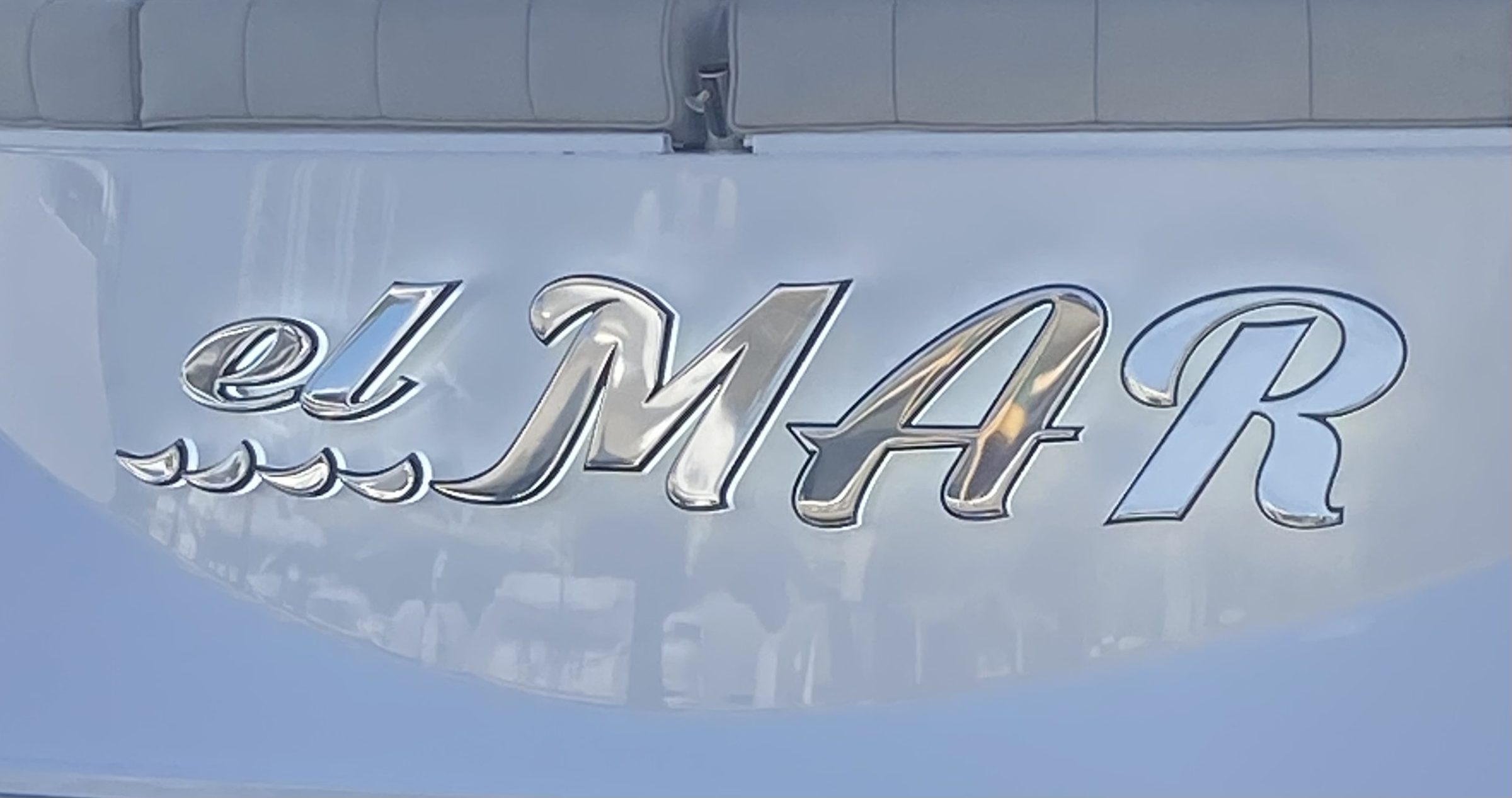 el MAR in mirror-polished stainless letters with a wave graphic, daylight close-up