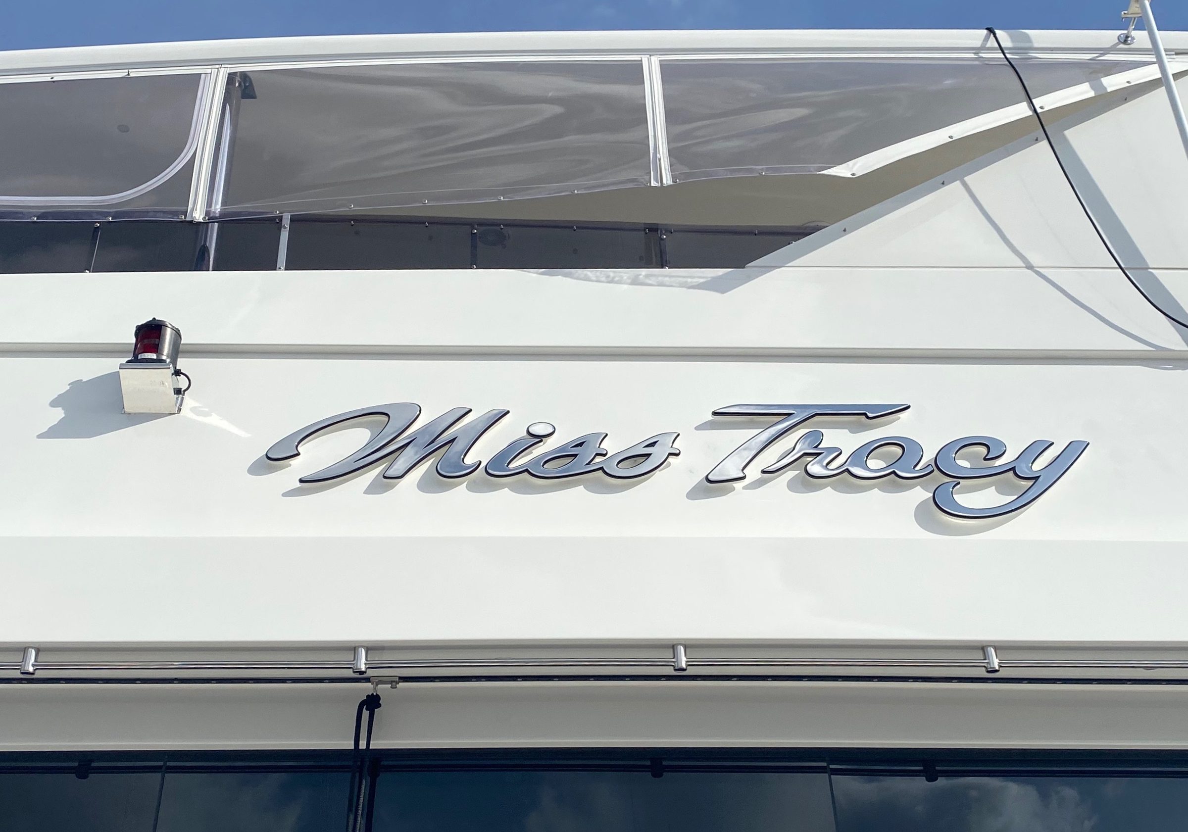 Miss Tracy in polished stainless script on a hull side in daylight